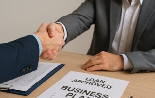 Χειραψία μεταξύ τραπεζίτη και επιχειρηματία – Αξιολόγηση φακέλου δανείου με business plan στο τραπέζι